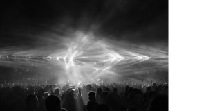 Mulțime la festival de muzică sub lumini de scenă puternice, noaptea
